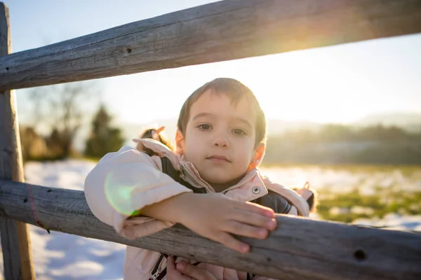 木製のカントリー フェンスの横に雪の中での小さな男の子 — ストック写真