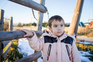 Ahşap ülke çitin yanında karda küçük çocuk
