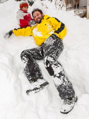 Baba ve oğul karda oynuyorlar.