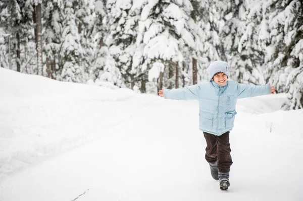 男孩走在白雪皑皑的乡间森林之路 — 图库照片