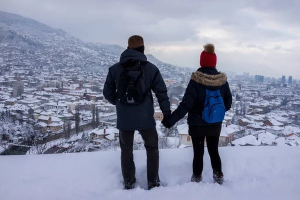 Romantic couple during travel looking at snow winter city