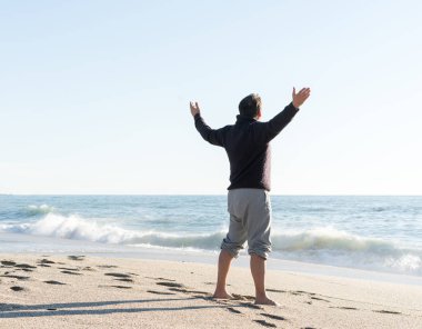 Adam kışın deniz sahiline gidiyor.