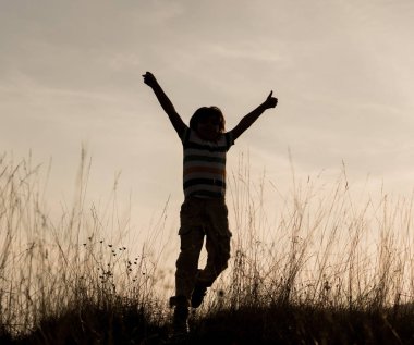 Gün batımında genç bir çocuk gölgesinde