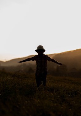 Gün batımında genç bir çocuk gölgesinde