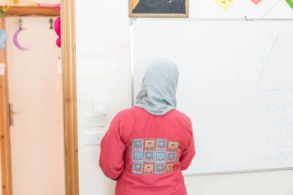 在课堂白板上书写的穆斯林女教师 — 图库照片