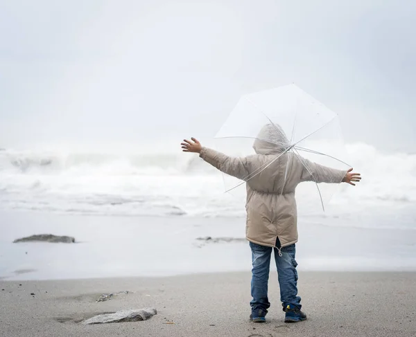 在冬季海滨带着雨伞的小男孩 — 图库照片