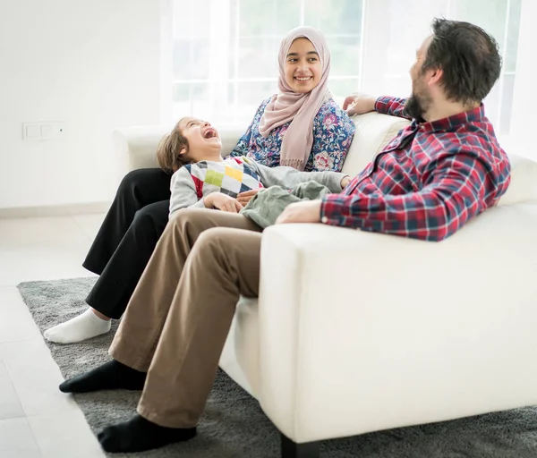 幸せなイスラム教徒の家族座っています上のソファで自宅での生活 — ストック写真