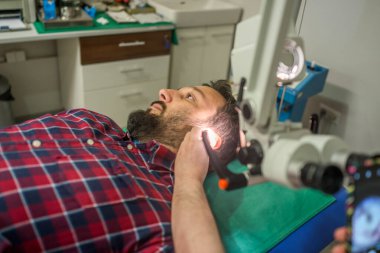 Hastanedeki doktor hasta kulağını kontrol ediyor.