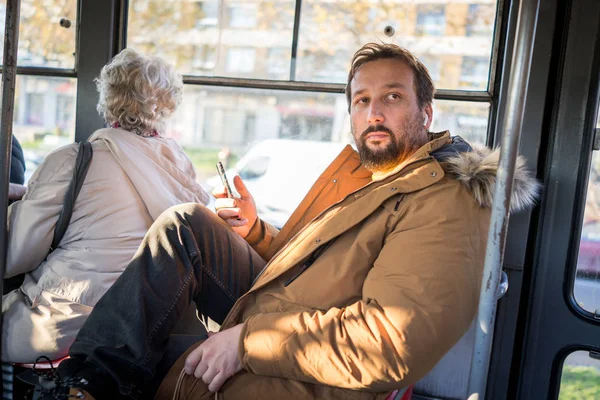 Homme Dans Les Transports Commun Assis Avec Smartphone Écoutant Musique Images De Stock Libres De Droits