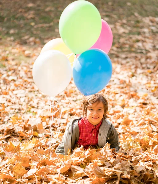 Çocuk Sonbahar Yapraklarında Balonlarla Eğleniyor — Stok fotoğraf