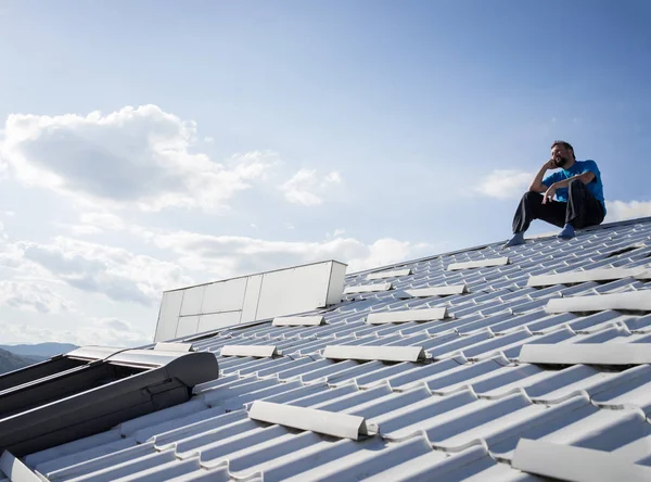 Man with phone on the top of house roof