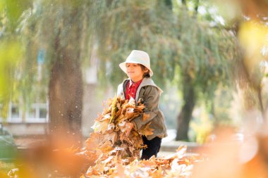 Sonbahar yapraklarında mutlu şirin çocuk.