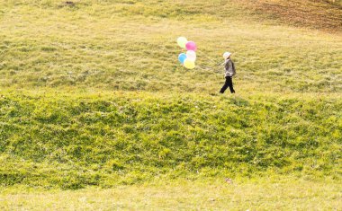 Balonlu çayırdaki küçük şirin çocuk.