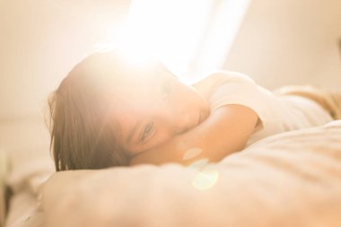 Lens ışığıyla yatakta küçük bir çocuk.