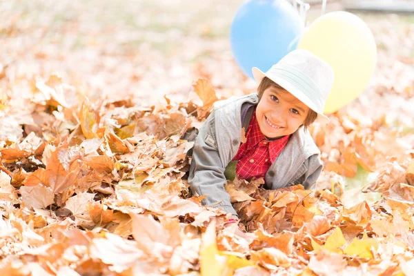 孩子们在秋天用气球在树叶里玩乐 — 图库照片