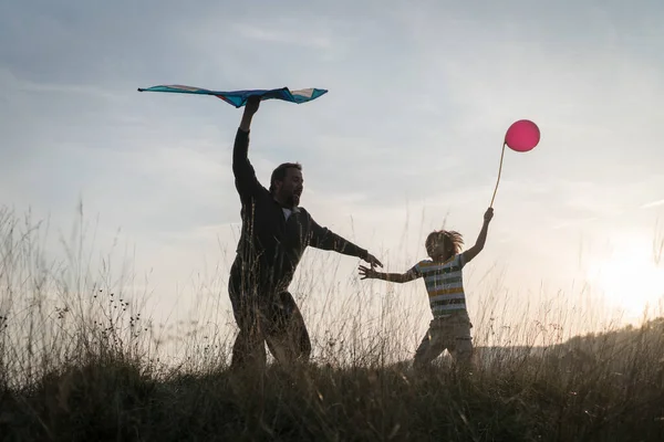 Padre Figlio Con Aquilone Sulla Sagoma Del Prato Tramonto — Foto Stock