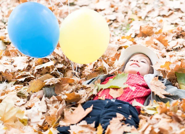 Çocuk Sonbahar Yapraklarında Balonlarla Eğleniyor — Stok fotoğraf