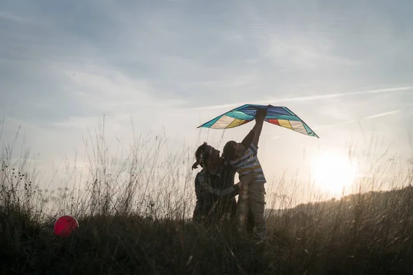 父と息子とともにカイトオン夕日草原シルエット — ストック写真