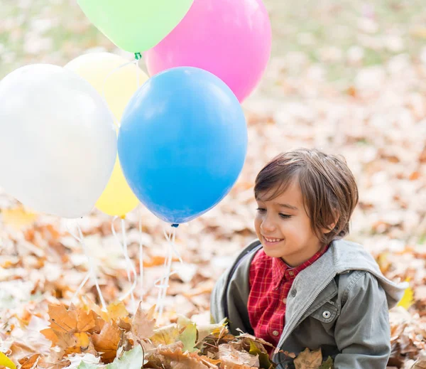 Çocuk Sonbahar Yapraklarında Balonlarla Eğleniyor — Stok fotoğraf