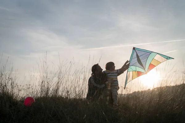 父亲和儿子在夕阳西下的草地上放风筝 — 图库照片