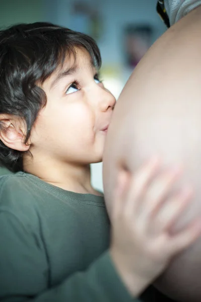 男孩抱着他怀孕的妈妈的肚子 — 图库照片