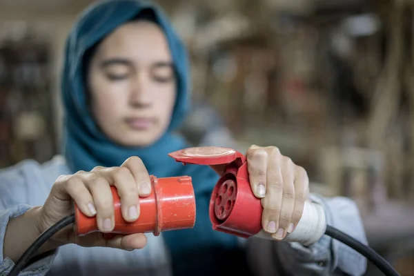 電気ケーブルを差し込むイスラム教徒の女の子 — ストック写真