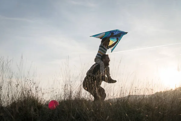 Vater Und Sohn Mit Drachen Auf Sonnenuntergang Wiesensilhouette — Stockfoto