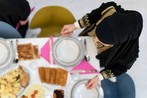 家族の食事のためのテーブルを準備するイスラム教徒の女の子 — ストック写真