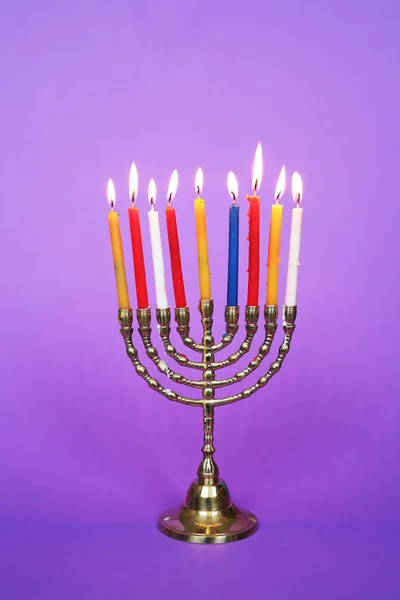 nine-branched menorah candlestick with burning candles over purple background, traditional festive decoration for Jewish holiday Hanukkah