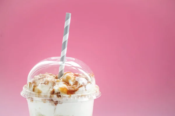 delicious caramel frappe coffee with drinking straw on pink background