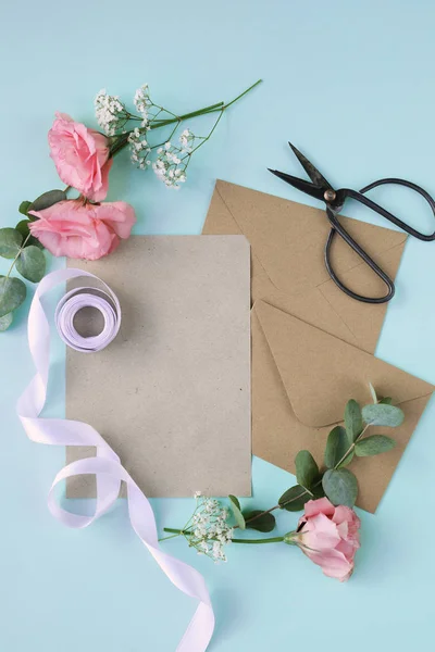 beautiful pink flowers, scissors, ribbon and envelopes on old wooden background