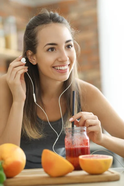 female food blogger with smoothie and earphones at kitchen, healthy food