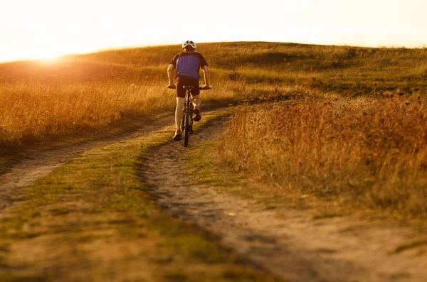 Male cyclist driving by rural dirt road