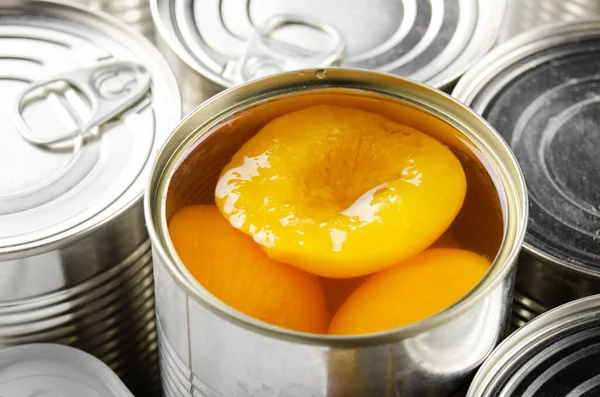 Canned peaches in just opened tin can. Non-perishable food
