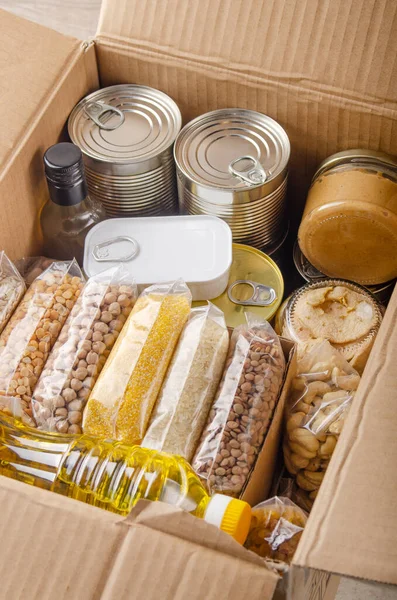 Set of uncooked foods in carton box prepared for disaster emergency conditions or giving away closeup view