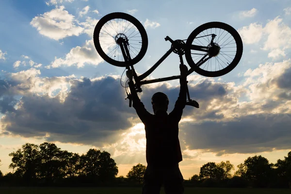 Ciclismo silueta jinete con bicicleta sosteniendo hasta —  Fotos de Stock