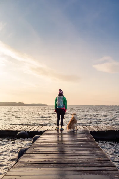 Mujer con perro disfrutar del amanecer en el lago, mochilero Fotos De Stock Sin Royalties Gratis