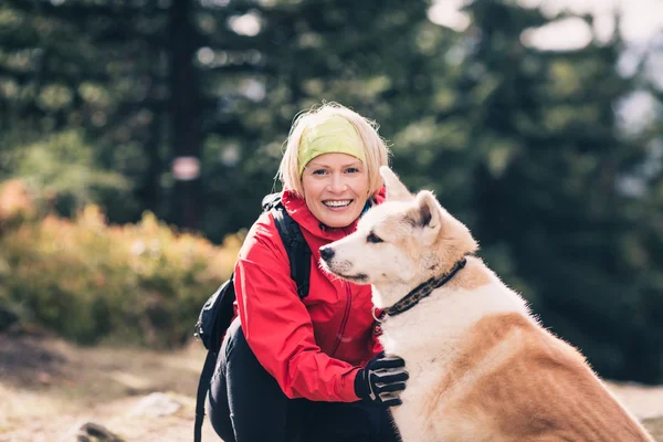 Girl hiking and walking with dog in autumn forest, friendship — Stockfoto