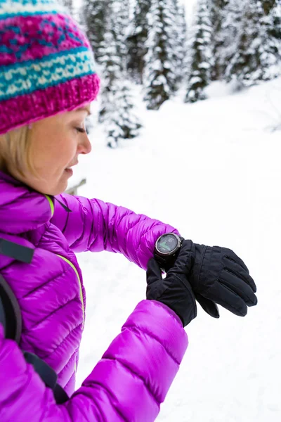 겨울 숲과 산 스포츠 시계를 확인 하는 여성 등산객 — 스톡 사진