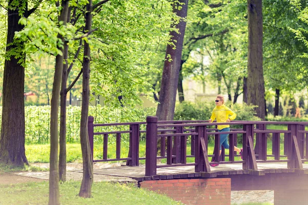 Γυναίκα δρομέας τρέχει τζόκινγκ στο πάρκο πράσινο το καλοκαίρι και ξύλα — Φωτογραφία Αρχείου