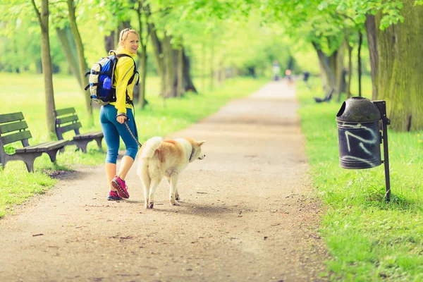 Kvinna löpare vandring med hund i sommar park — Stockfoto