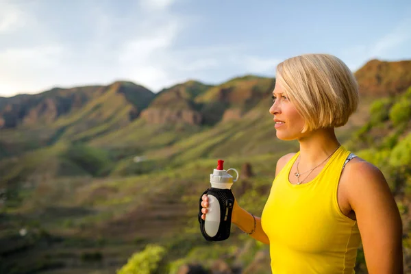 Mutlu kadın iz runner içme suyu dağlarda — Stok fotoğraf