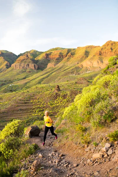 Mulher correndo em montanhas rochosas no pôr do sol de verão — Fotografia de Stock