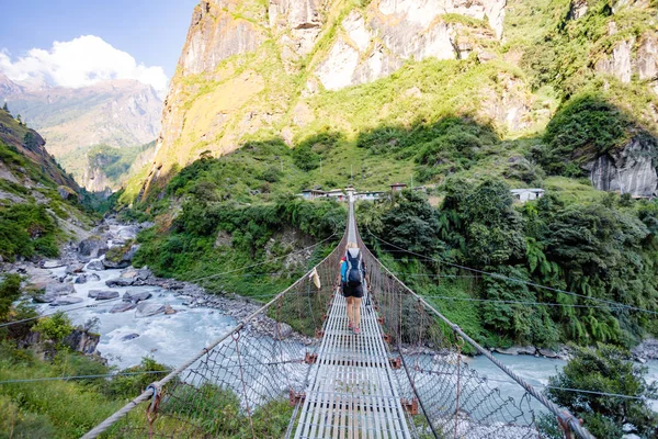 女背包客过境悬索桥在喜马拉雅山脉尼泊尔 — 图库照片