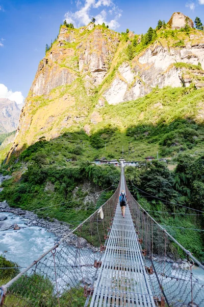 Женщина-турист, пересекающая подвесной мост в Гималаях Непал — стоковое фото