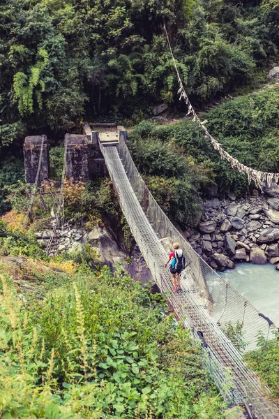 Vrouw backpacker kruising hangbrug in Nepal Himalaya — Stockfoto