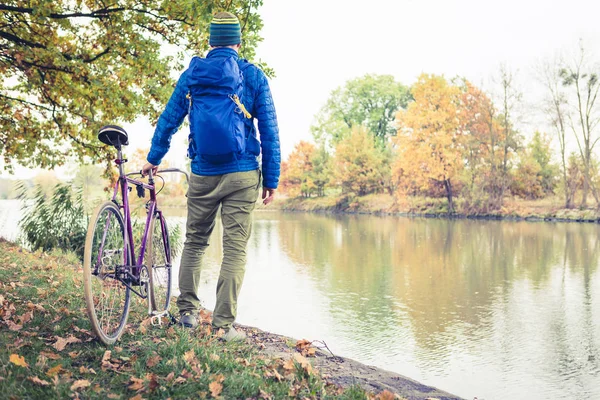 Man met racefiets kijken met uitzicht op de rivier in park — Stockfoto