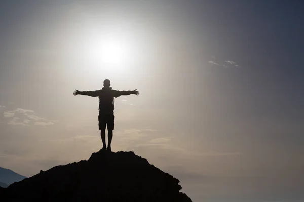 Людина з простягнутими руками святкує схід сонця в горах — стокове фото