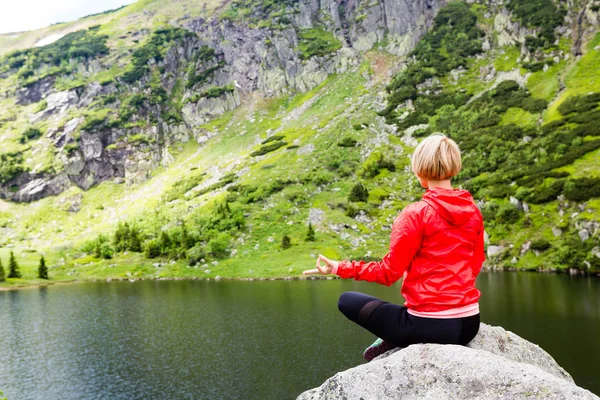 Mulher meditando em pose de ioga na frente do lago da montanha — Fotografia de Stock