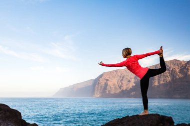 Woman meditating in yoga dancer pose, inspiring landscape clipart